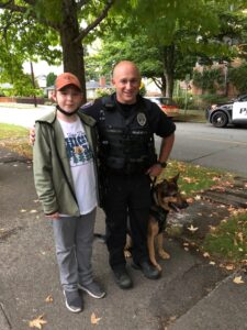 Sam stands with a police officer and his K9 partner.